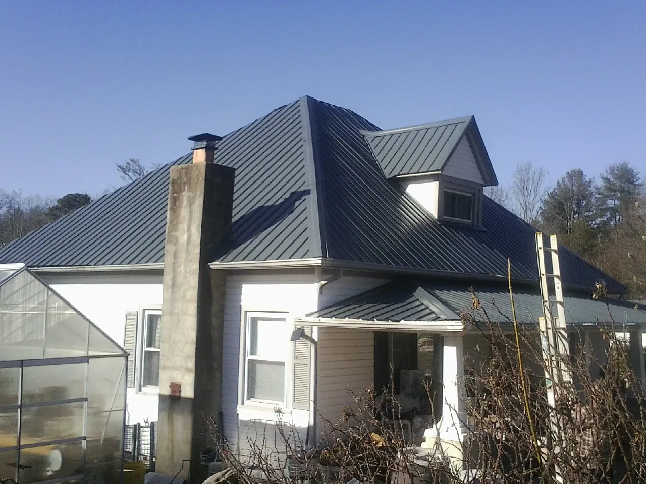Dark blue standing seam metal roof on a white farmhouse with dormer — Slate & Tile Roof Repair by Roofing Brothers in East Dennis