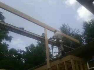 Carpenter setting a ridge beam over a new addition frame — Ice Dam Removal by Roofing Brothers in East Dennis