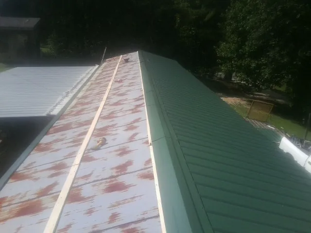 Old rusted panels beside newly installed green metal roofing — Wind Damage Roof Repair by Roofing Brothers in East Dennis