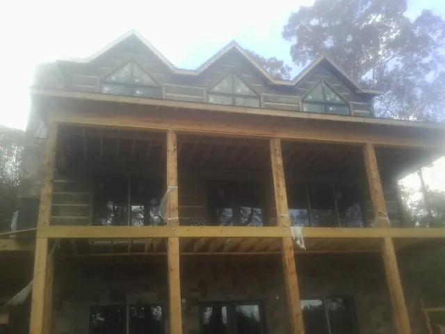 Dormers and porch framing on a large log home under construction — Roof Coating work by our crew in East Dennis