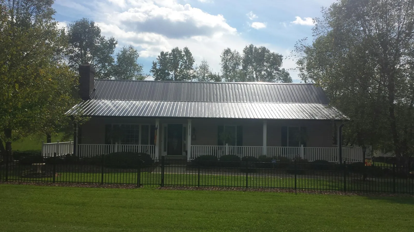 Gray metal roof on a brick ranch with a full width front porch — Gutter Guard Installation work by our crew in East Dennis