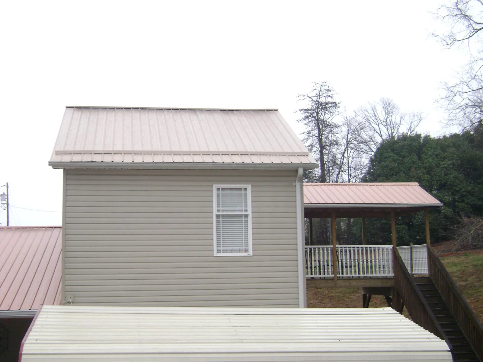 Tan metal roofs on a two story addition and attached porch, from a Roof Replacement job in East Dennis