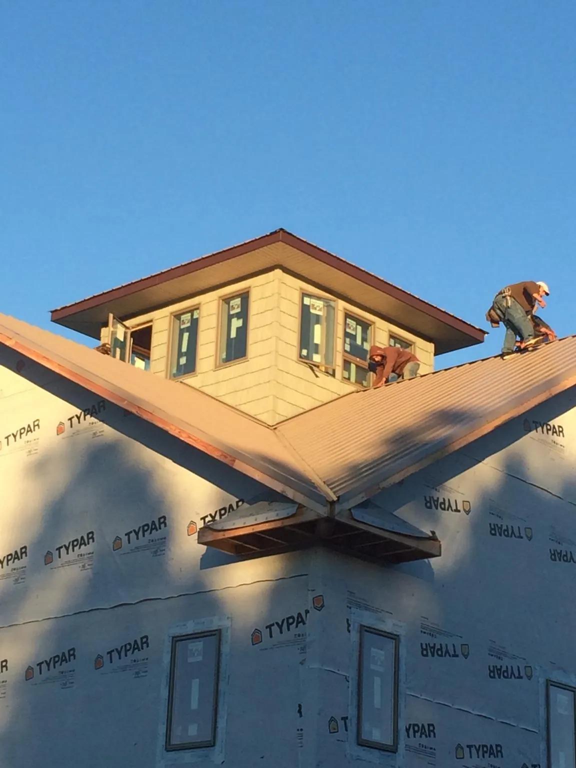 Roofers working around a rooftop cupola on a new metal roof at sunset — Roof Waterproofing in East Dennis by Roofing Brothers